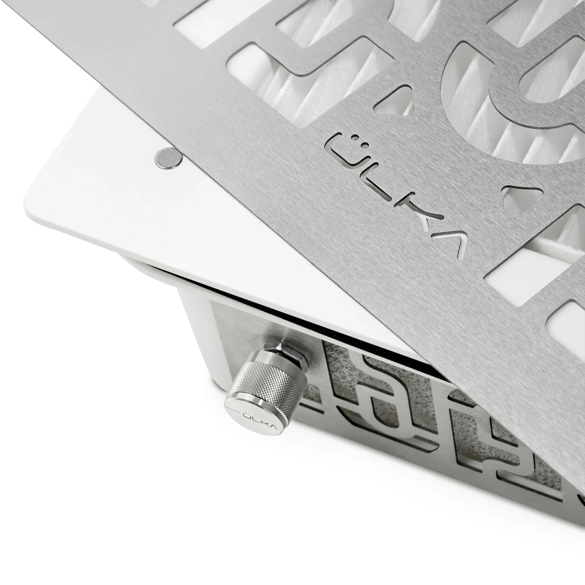 Close-up of a white ULKA AERO built-in dust collector with its metal grille, ULKA logo and control knob