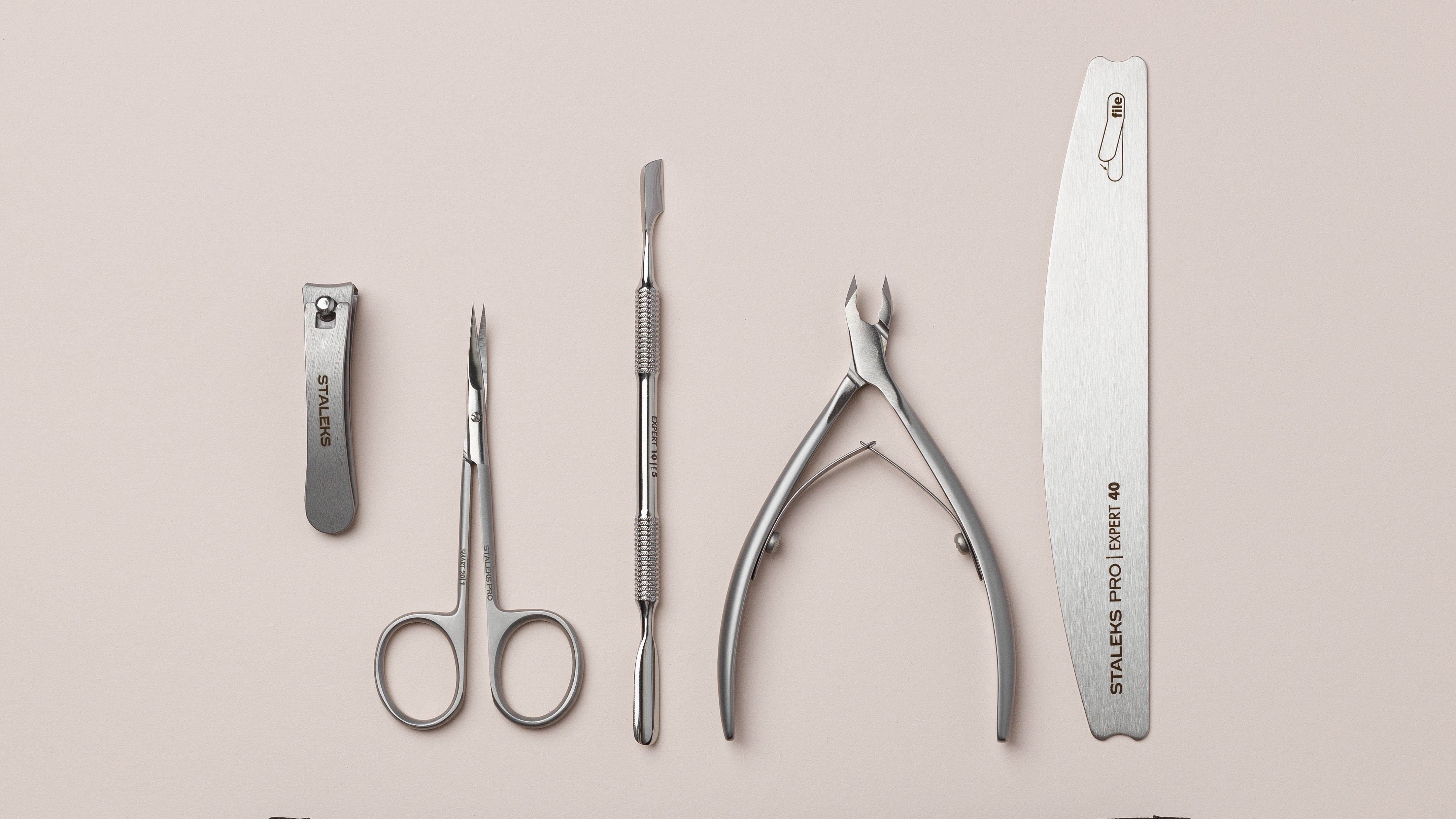 Set of nail care tools with a Staleks Pro case on a beige background